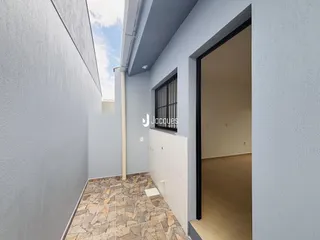 Corredor interno de uma residência com piso de cerâmica e paredes cinzas.