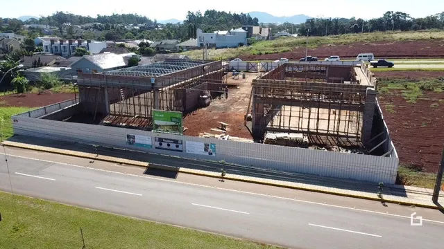 Vista externa de um terreno em construção com estrutura de concreto exposta.