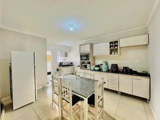 Vista interna de uma cozinha com armários brancos e mesa de jantar em Lajeado.