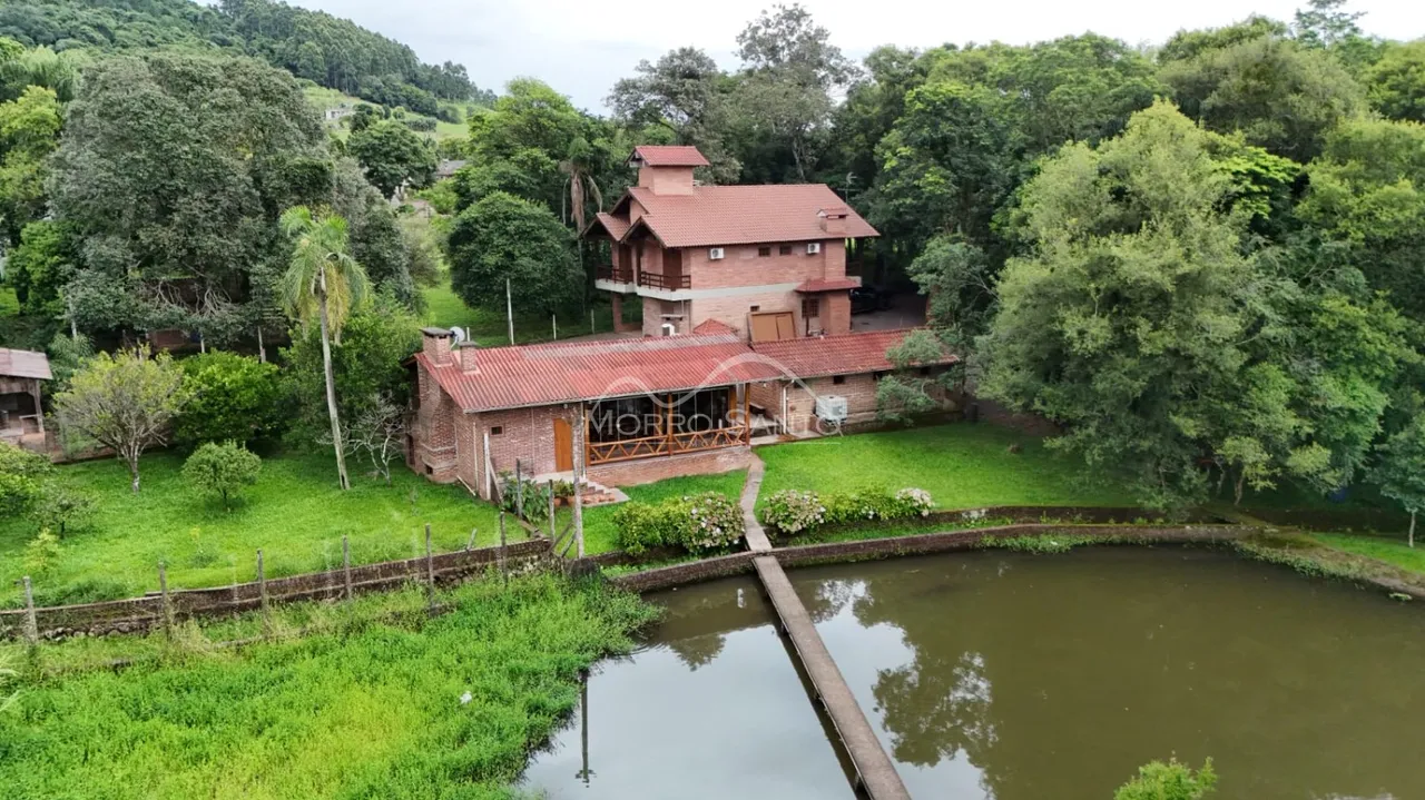 Fachada de uma casa em Lajeado, Brasil, cercada por vegetação e um corpo d'água.