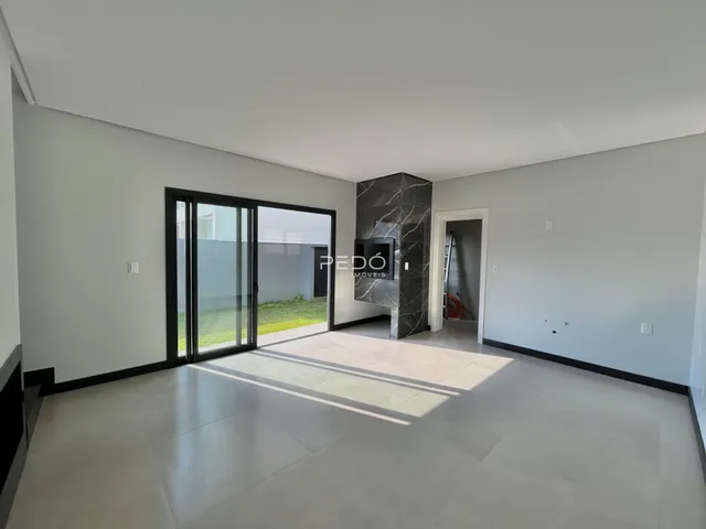 Ambiente interno de uma sala com piso claro e porta de vidro que dá acesso ao exterior.