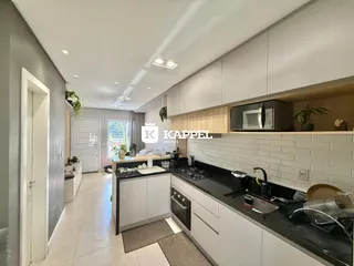 Cozinha moderna com armários brancos e bancadas escuras.