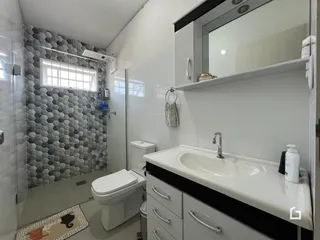 Foto de um banheiro com revestimento hexagonal cinza e louças brancas.