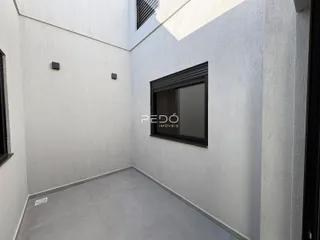 Vista interna de um espaço com paredes brancas e piso cinza.