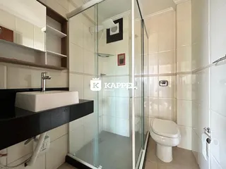Banheiro com box de vidro e revestimento branco.