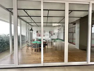Sala de jantar com piso de madeira e grandes portas de vidro.
