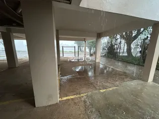 Vista externa de uma área pavimentada com pilares de concreto.