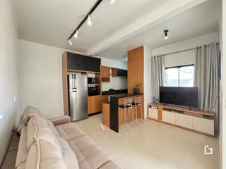 Sala de estar com cozinha integrada e sofá em um apartamento.
