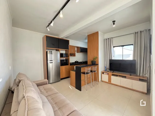 Sala de estar com cozinha integrada e sofá em um apartamento.