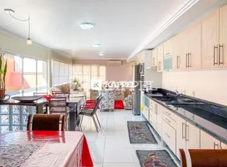 Foto de uma cozinha com armários claros e bancada escura.