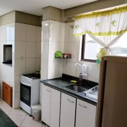 Foto de uma cozinha interna com armários brancos e bancada escura.