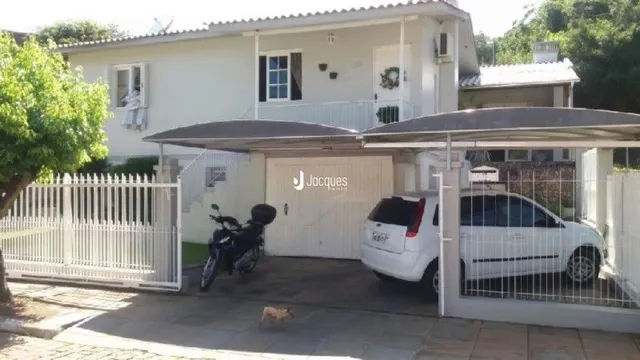 Fachada de uma casa em Lajeado, Brasil com cerca e portão branco.