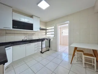 Foto de uma cozinha com armários brancos e piso de cerâmica clara.