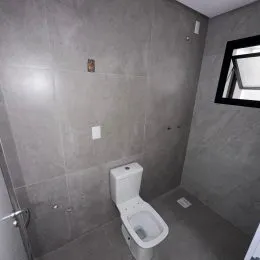 Foto de um banheiro com vaso sanitário e parede lisa.