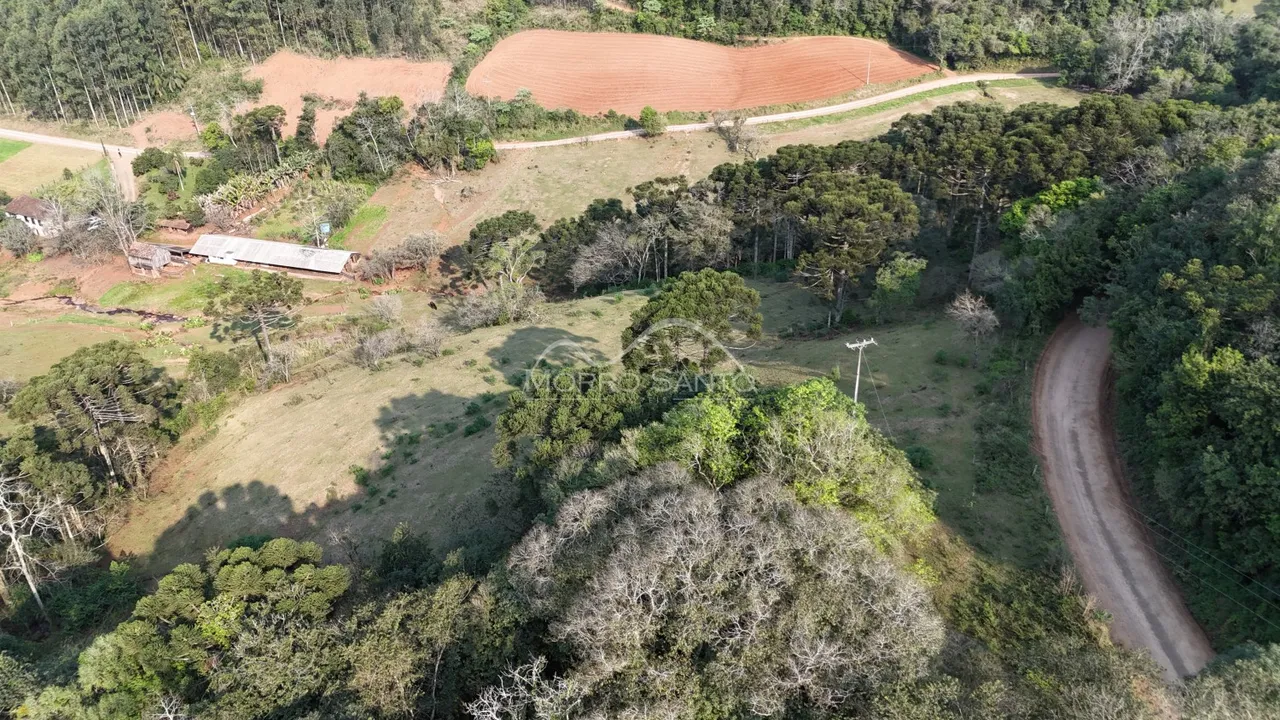 Vista aérea de uma área rural com campos e vegetação densa na propriedade.