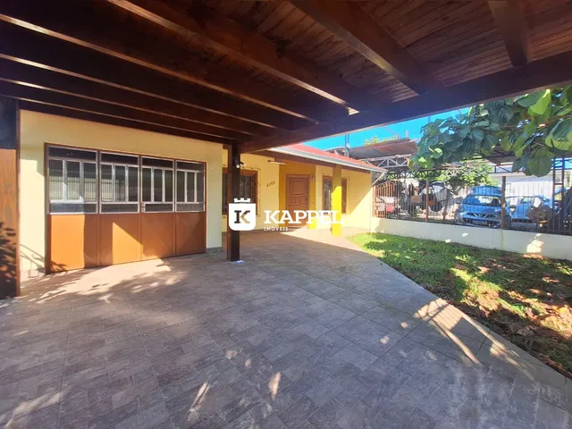 Exterior da casa mostrando a garagem e a entrada pavimentada.
