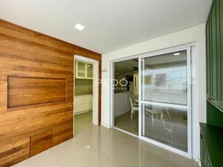 Interior de uma sala com revestimento de madeira e porta de vidro.