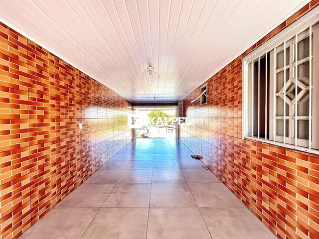 Corredor interno com paredes de tijolos aparentes e piso de cerâmica.