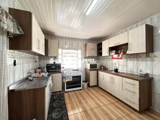 Uma cozinha com armários de madeira e piso de madeira clara.
