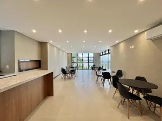 Ambiente interno moderno com grandes janelas e área de jantar.