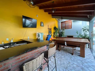 Vista de uma área de cozinha com parede amarela e bancada de tijolos.