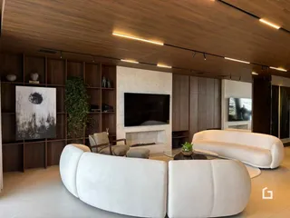 Sala de estar moderna com sofá branco e painel de madeira.