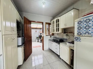 Vista interna de uma cozinha com armários brancos e piso de cerâmica.