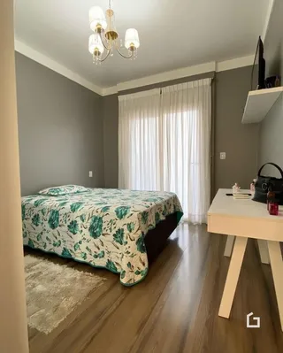 Quarto com cama e piso de madeira clara.