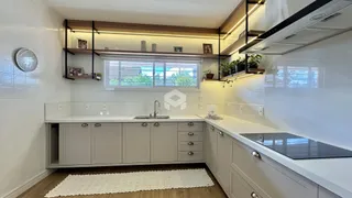 Vista da cozinha com armários brancos e bancadas claras.
