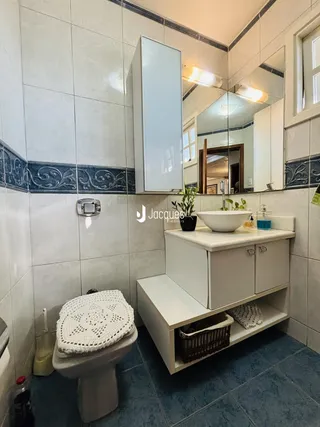Foto de um banheiro com revestimento de azulejos e bancada branca.