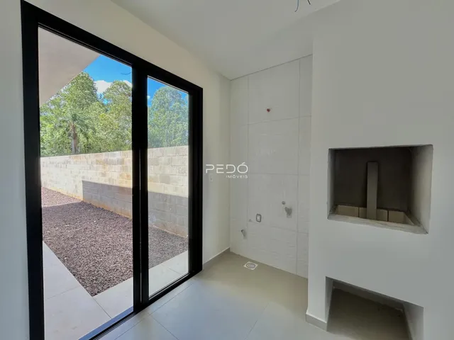 Vista interna de um ambiente com portas de vidro que dão acesso a uma área externa de cascalho.
