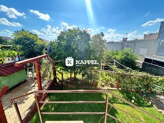 Vista externa de um terraço com vegetação e grade metálica.
