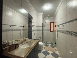 Foto de um banheiro com revestimento cerâmico e box de vidro.