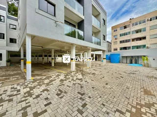 Foto da área externa pavimentada em frente ao prédio residencial.