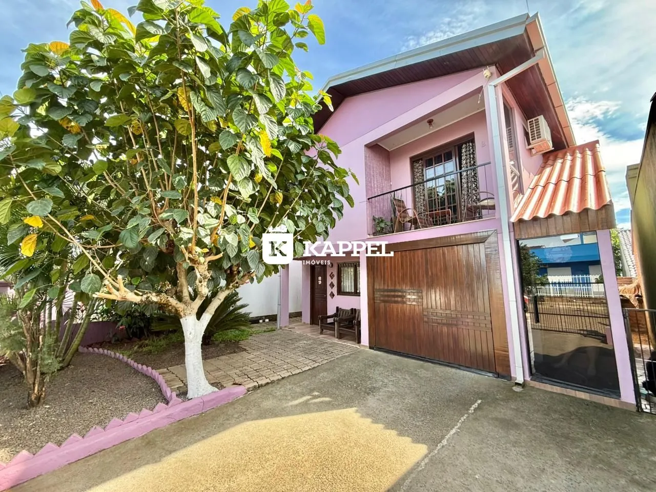Fachada de uma casa rosa em Lajeado, com garagem e jardim na frente.