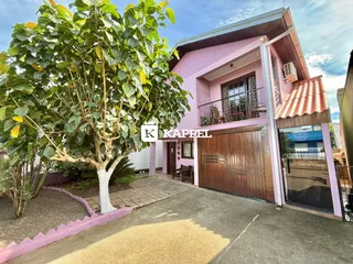 Fachada de uma casa rosa em Lajeado, com garagem e jardim na frente.
