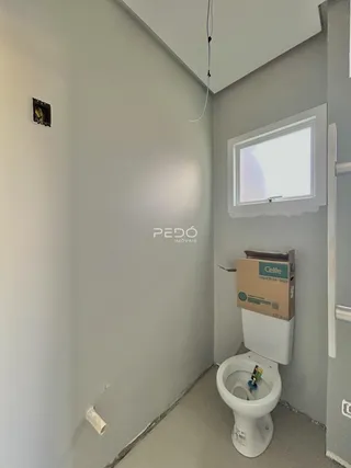 Vista de um corredor interno com um vaso sanitário e uma janela.