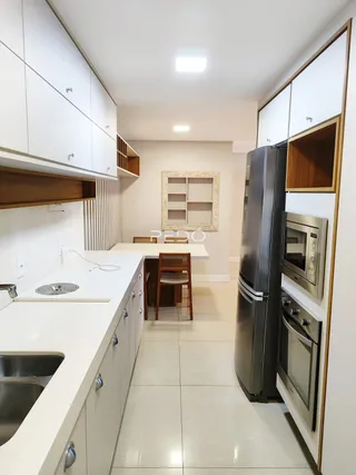 A cozinha moderna com armários brancos e piso claro.