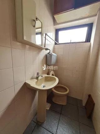 Foto de um banheiro com revestimento cerâmico nas paredes e piso escuro.