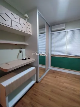 Ambiente interno de uma sala com piso de madeira clara e paredes brancas.