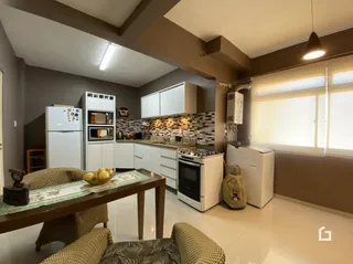 Sala de estar com mesa de jantar e armários brancos.