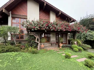 Fachada de uma residência em Lajeado, Brasil, com jardim exuberante e vegetação.
