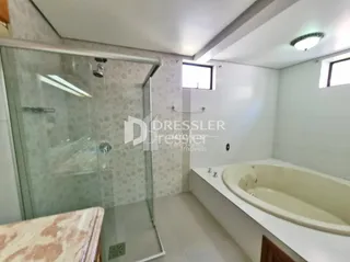 Banheiro com box de vidro e banheira em um imóvel.