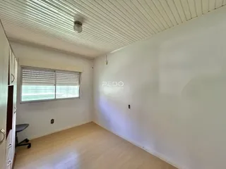 Ambiente interno de uma sala com piso claro e teto de painel branco.