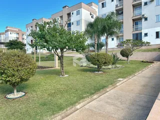 Paisagem de jardim com gramado e árvores em frente a edifícios residenciais.
