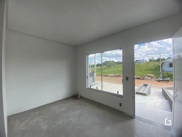 Ambiente interno de uma sala vazia com piso de concreto e janela para o exterior.
