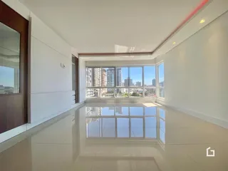Sala de estar com piso claro e grandes janelas com vista para a cidade.