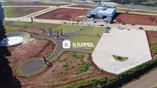 Vista aérea de um terreno com áreas de paisagismo e um edifício comercial ao fundo.