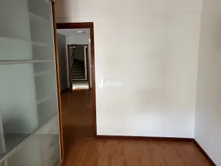 Vista de um corredor interno com piso de madeira.