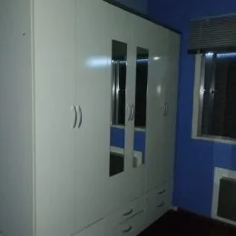 Armários brancos de armário instalados em uma parede escura.